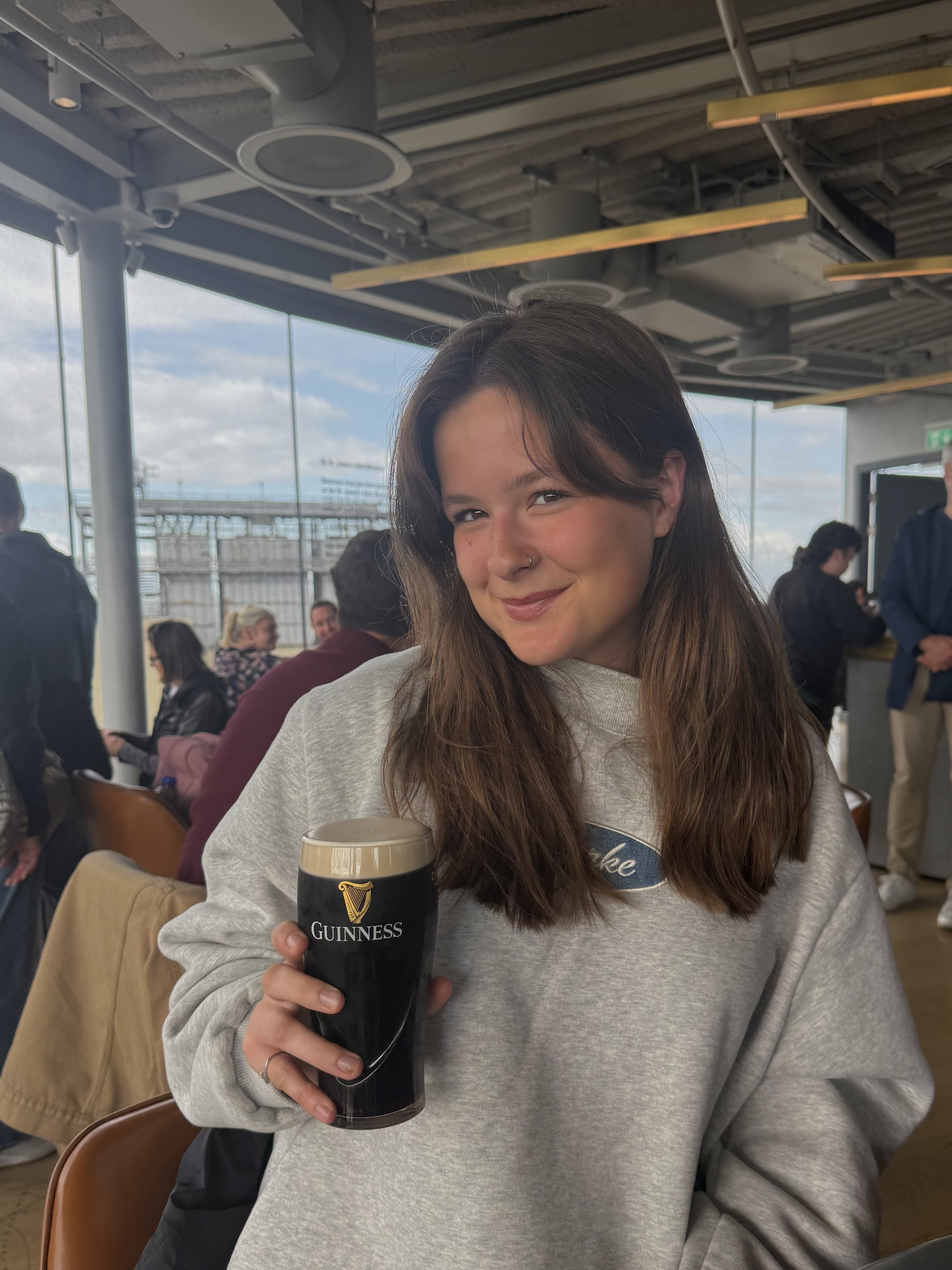 a girl with brown hair holding a guinness glass, this is Mia the author
