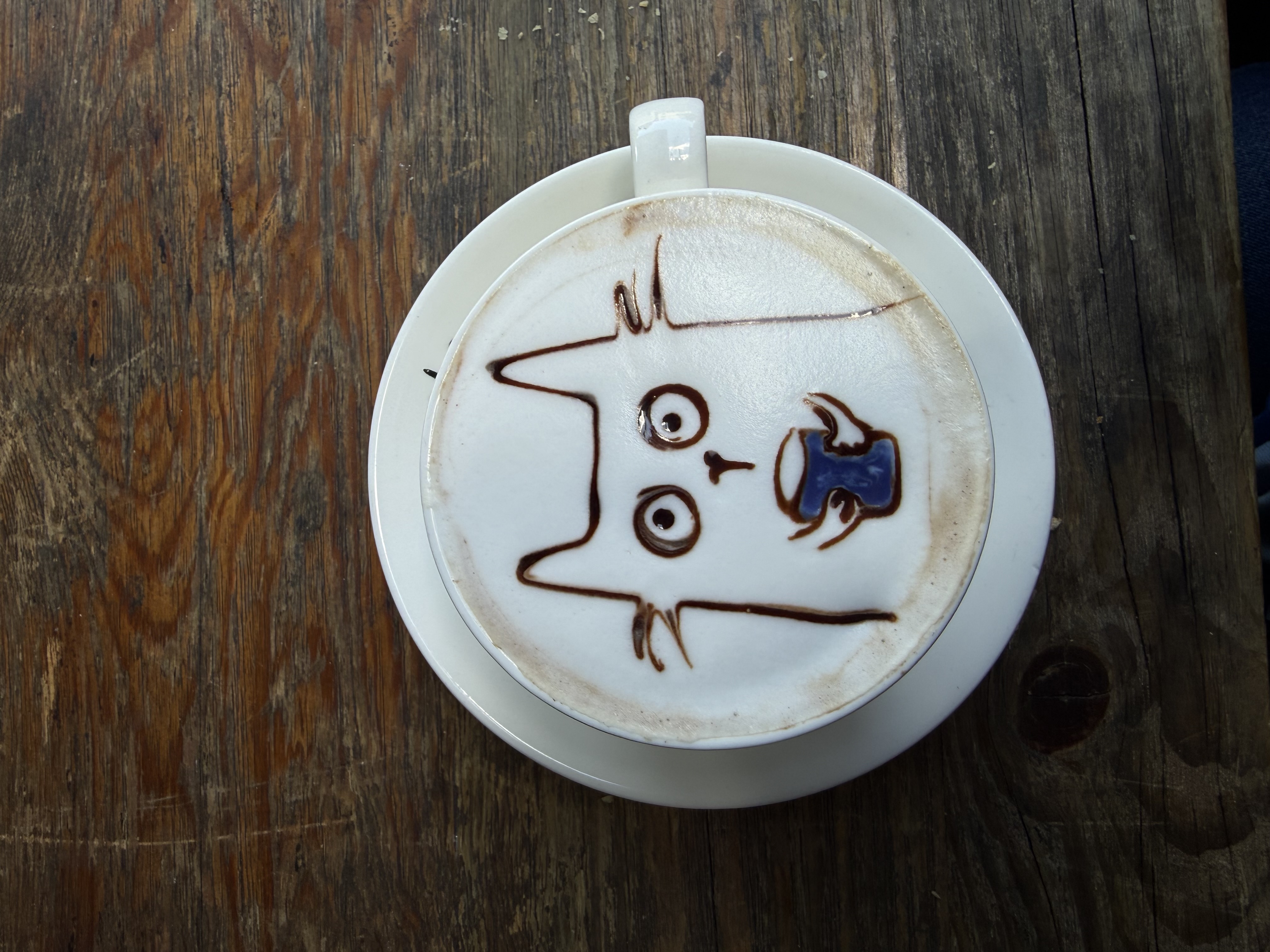 coffee in a mug with a design on top of a cat holding a coffee mug