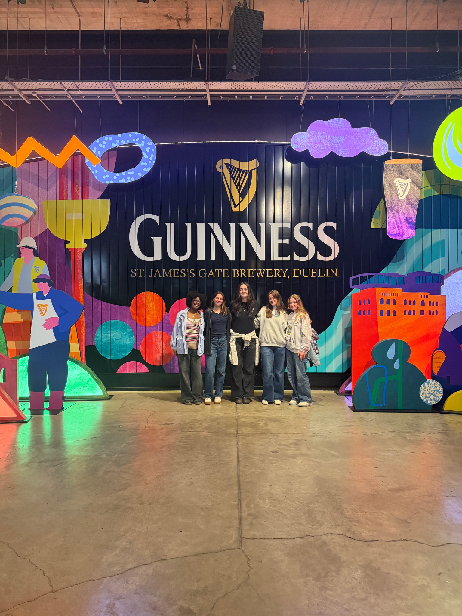 group of 5 in front of colorful Guinness sign