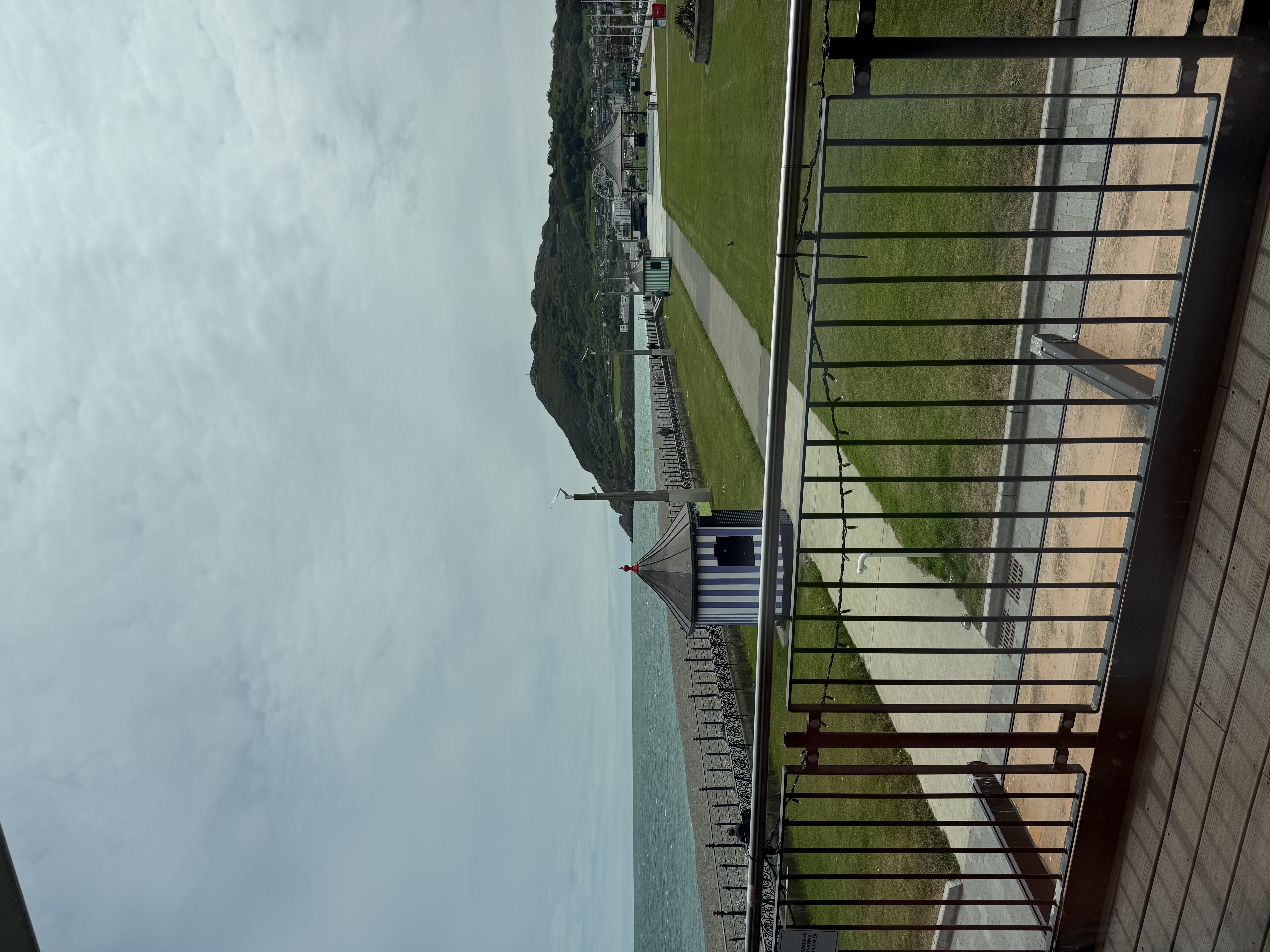 out the window where there is a balcony overlooking water and a cliff